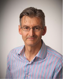An image of Professor Alex Breeze wearing a lilac shirt and glasses