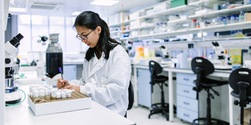 A research student writing as she works in a lab.