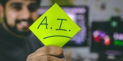Man holds a post-it note that which reads AI