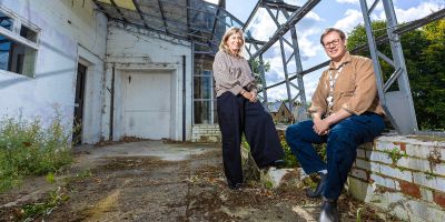 Denise mcardle and seb stroud in a large greenhouse smiling at the camera