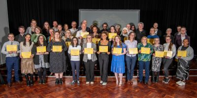 Winners of the Partnership Awards 2024 smile at the camera holding their yellow certificates.