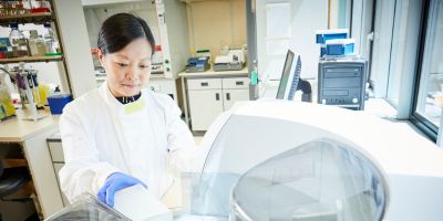 A woman in a white lab coat conducts an experiment in a laboratory.