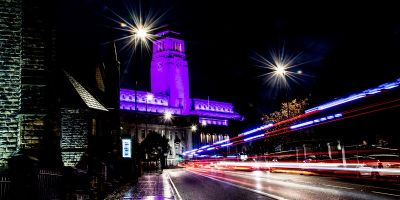 An image of the University of Leeds Parkinson building illuminated in purple light.