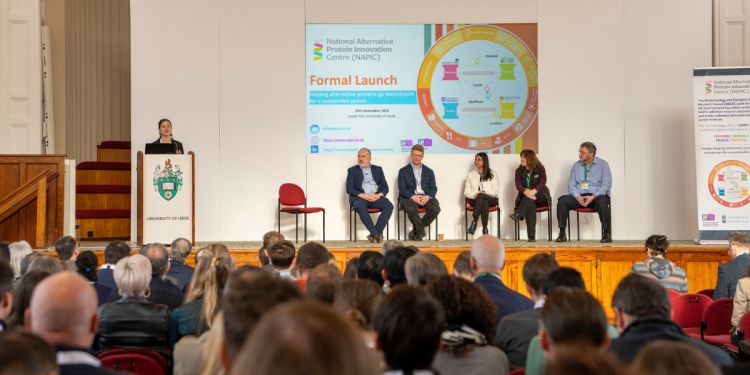 5 Members of a panel sit on chairs on a stage