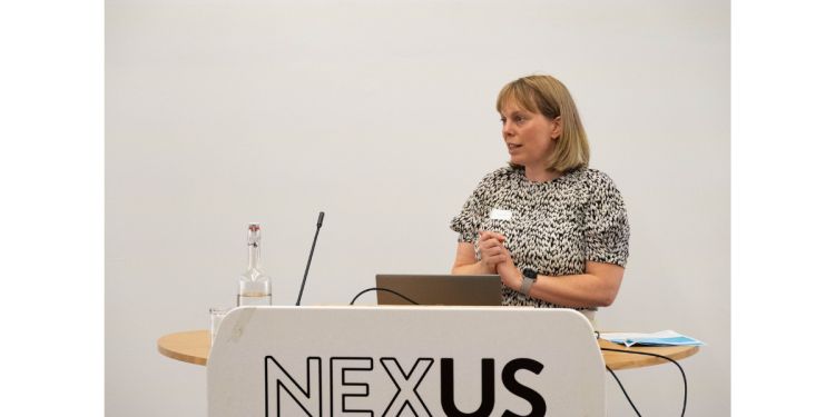 Sarah astill presents at the reimagine ageing showcase behind a podium. The podium reads nexus