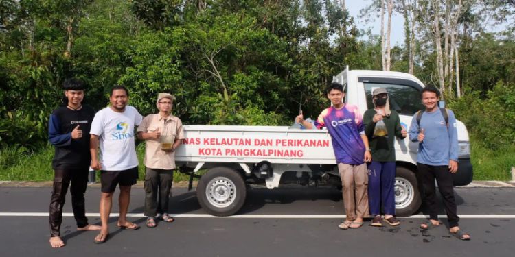 Veryl hasan and 5 students from universitas bangka belitung smile at the camera in front of a white van. They are standing on a paved road lined with trees.