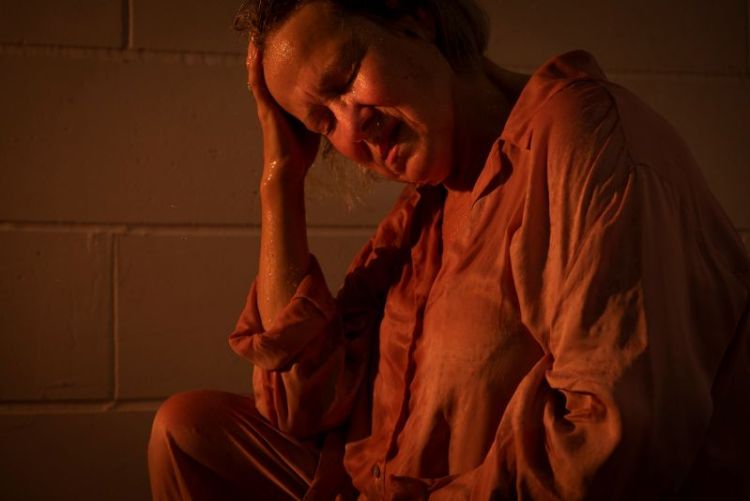 Image from an arts project showing a woman holding her head in a darkly lit room
