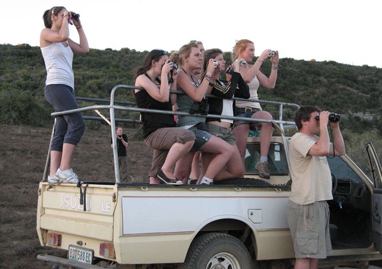 Students observe through binoculars on the back of a jeep