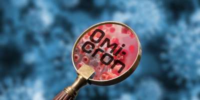A magnifying glass magnifying a graphic of an omicron virus